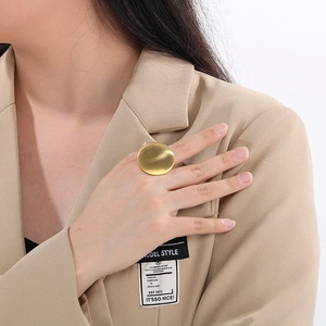 Detail of matte gold minimalist oval ring on hand with elegant professional styling