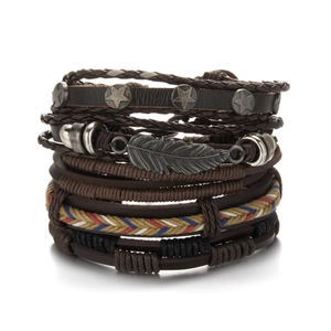 Detail of vintage layered leather bracelets set with metal star and feather charms