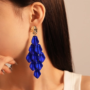 Detail of dark blue acrylic petal tassel earrings with gold metal stud on model