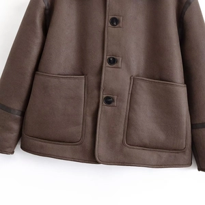 Détail de la veste en daim marron foncé avec grandes poches et fermeture à boutons