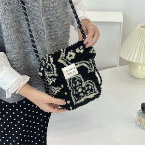 Gros plan sur un sac bandoulière en laine d'agneau noire avec sangle à motifs