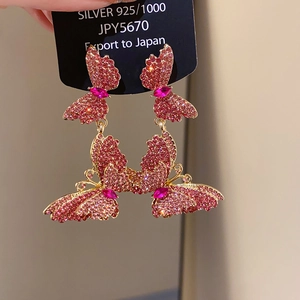 Detailed macro view of pink butterfly earrings with crystals and silver needle studs