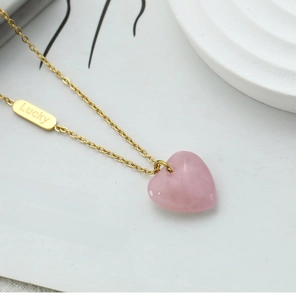 Close-up of heart rose quartz pendant with Lucky tag on 18K gold plated steel chain
