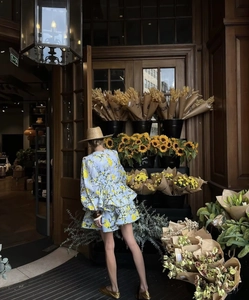 Detail of light blue floral dress showing yellow prints and tiered ruffle skirt