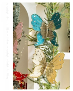 Close-up of elegant fabric butterfly ornaments with gold glitter and rhinestones on a tree
