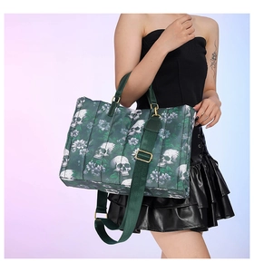 Detail of dark green tote bag featuring skull floral prints and wide shoulder strap