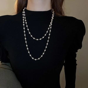 Gros plan d'un collier de perles à double rangée sur un col roulé noir élégant