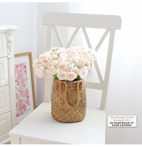 Detail of four champagne camellia bouquets in a straw basket on a white wooden chair