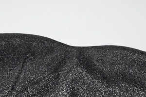 Détail du tissu noir scintillant avec paillettes argentées sur la robe col en V