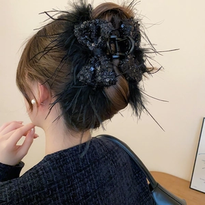 Macro detail of a black sequined bow hair claw clip with fluffy feather trim in hair