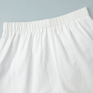Detail of elastic waistband on white cotton-linen shorts with natural woven texture