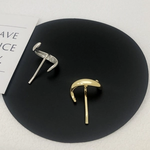 Polished gold and silver C-shaped hoop earrings on black pad for modern women
