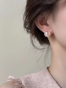 Close-up of pink mermaid pearl stud earrings showing pearlescent texture on model ear