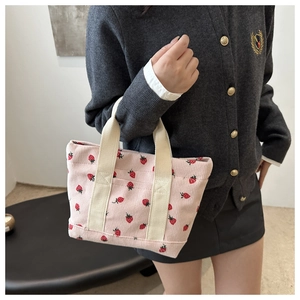Detailed texture of pink corduroy fabric with cute red strawberry patterns on the handbag