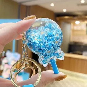 Lollipop-shaped quicksand keychain with blue flowers, golden hook and blue bow tie charm