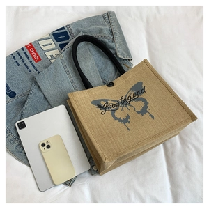 Detailed view of beige linen tote bag with grey butterfly print and Love legend text
