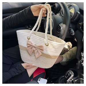 Detail of hand-woven cotton rope tote bag in beige with a silk champagne bow decoration