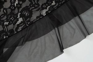 Macro shot of elegant floral lace and mesh patchwork on a black sleeveless summer dress