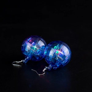 Close-up of glowing blue disco ball earrings with internal LED lights on black background