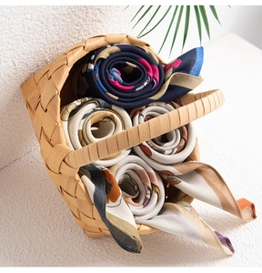 Rolls of geometric printed silk-like scarves neatly displayed in a woven basket