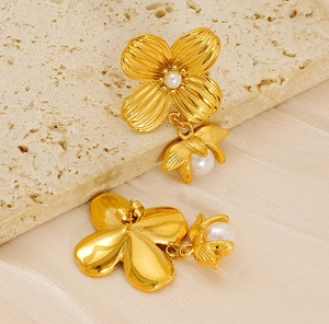 Detail of flower stud earrings in gold with pearl center and radial petal texture