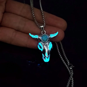 Luminous bull skull necklace with turquoise stone inlay glowing in dark blue light