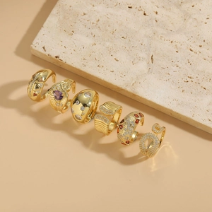 Detail view of 14K gold plated rings with colorful zircon stones on a beige backdrop