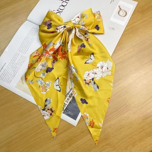 Detail of yellow satin bow hair clip with floral patterns on a magazine surface