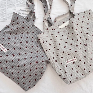 Détail du sac cabas en toile à carreaux avec pois rouges et broderies de nœuds fins