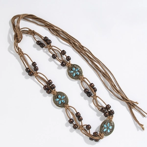 Detail of bohemian hand-woven belt with wooden beads and bronze floral medallions