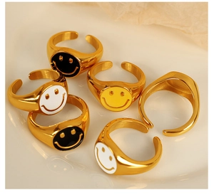 Group of 18K gold-plated smiley face open rings displayed on a textured plate