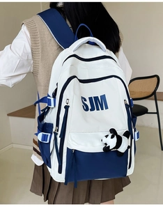 Blue and white canvas backpack with panda pendant shown from a back-view perspective
