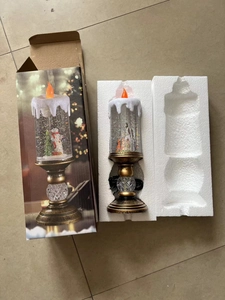 Detail view of a Christmas snow globe candle light with snowmen inside and foam packaging