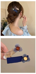 Dettaglio di due fermagli per capelli con fiori blu, petali traslucidi e perle d'oro