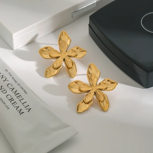 Detailed close-up of double-layer gold flower earrings on a luxury jewelry box