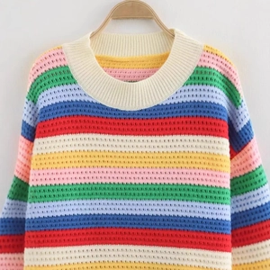Pull en maille à rayures arc-en-ciel avec franges présenté sur un cintre mural blanc