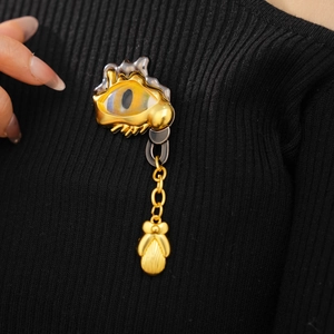 Detailed view of the vintage eye brooch with gold and silver tones on black fabric