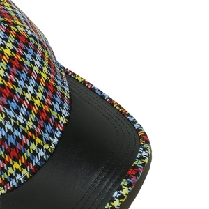 Detailed macro view of colorful houndstooth fabric and black leather brim on baseball cap