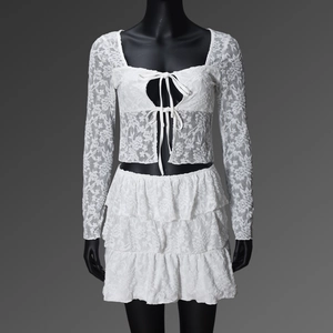 Detail of white floral lace texture and ribbon ties on the long sleeve crop top