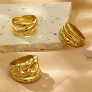 Tre anelli geometrici spessi placcati oro 18k su tessuto di seta e sfondo marmo