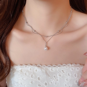 Détail d'un collier double épaisseur en argent avec perle blanche porté par un mannequin