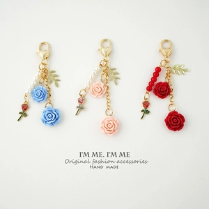 Close-up of resin rose keychains with gold heart-shaped clasps and metal leaf charms