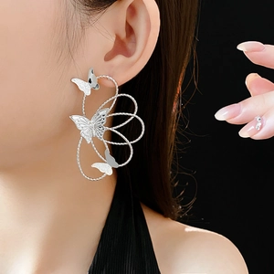 Detailed view of silver hollow butterfly earrings on model with an asymmetric design