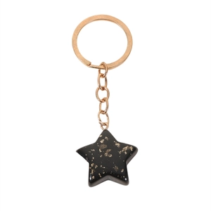 Detail of star-shaped keychain with black translucent resin and gold foil flakes