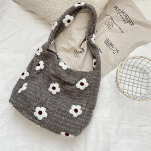 Dettaglio della borsa in maglia con morbida trama peluche e ricamo floreale bianco