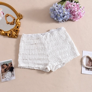 Détail de short en dentelle blanche à volants avec petit nœud et décor floral élégant