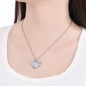 Close-up of silver irregular pleated heart pendant necklace on model neck
