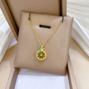 Detailed view of a gold lemon slice pendant with green crystals in a jewelry box