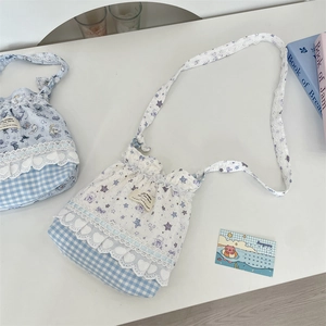 Détail de broderie d'ours sur des sacs à cordon en coton avec bordure en dentelle
