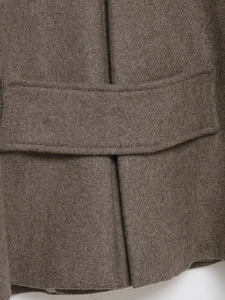 Makroaufnahme des dunkelbraunen Wollmantels mit Details zu Tasche und Stoffstruktur